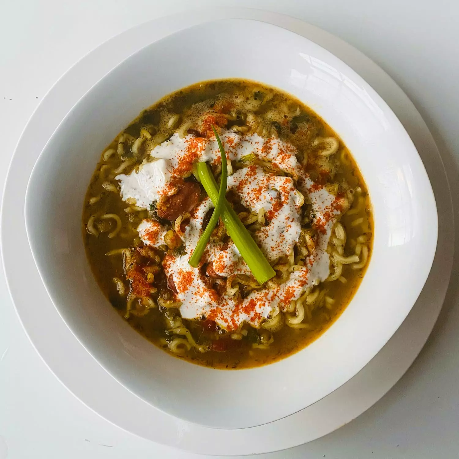 Thai noodle dish with a top down view of the dish on a table with bright red spices sprinkled over the dish