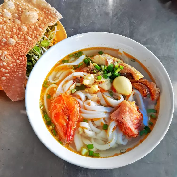 Fresh noodle dish with crunchy chinese bread to the left side